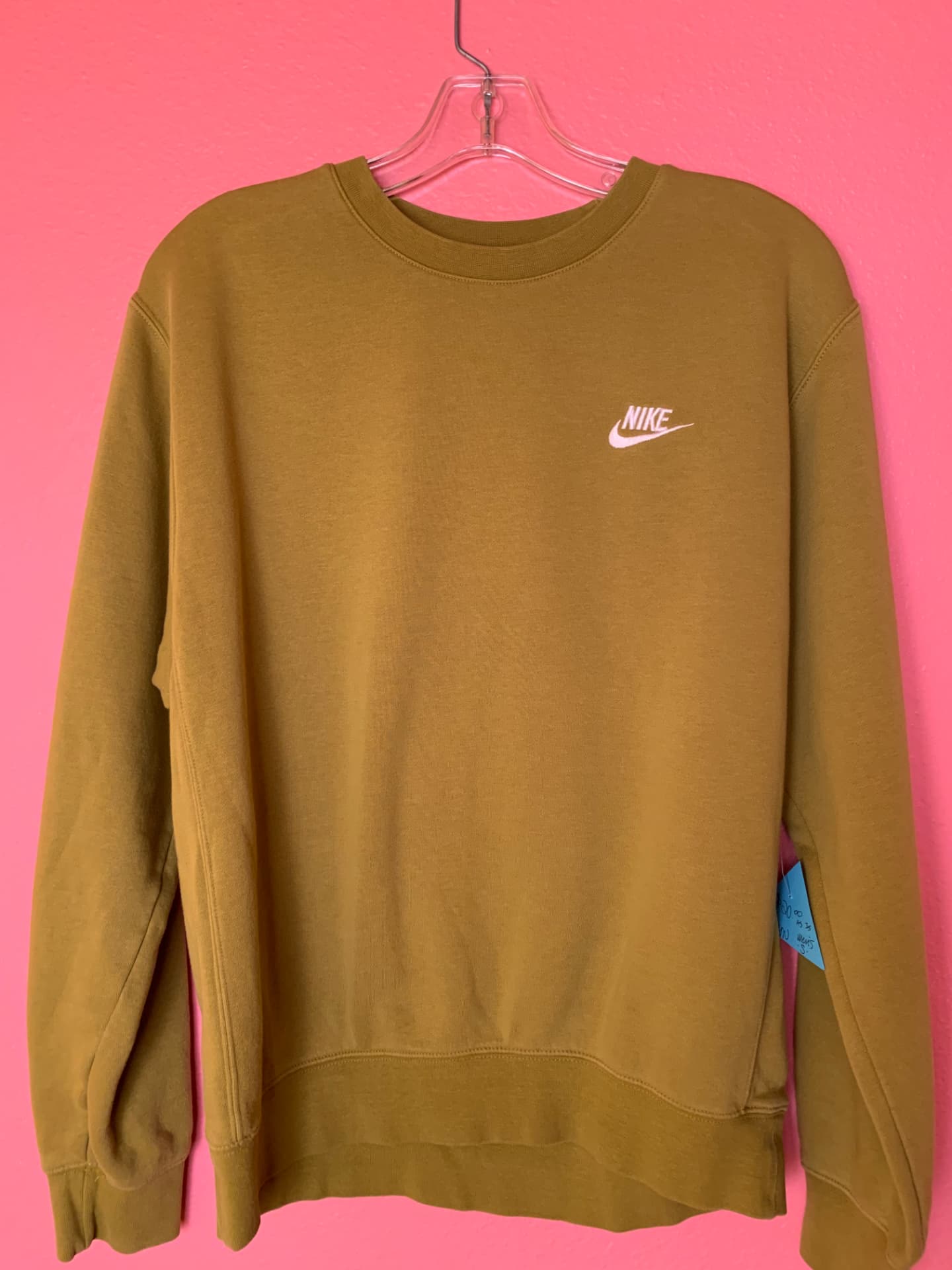 Mustard Nike crewneck sweatshirt on a pink wall