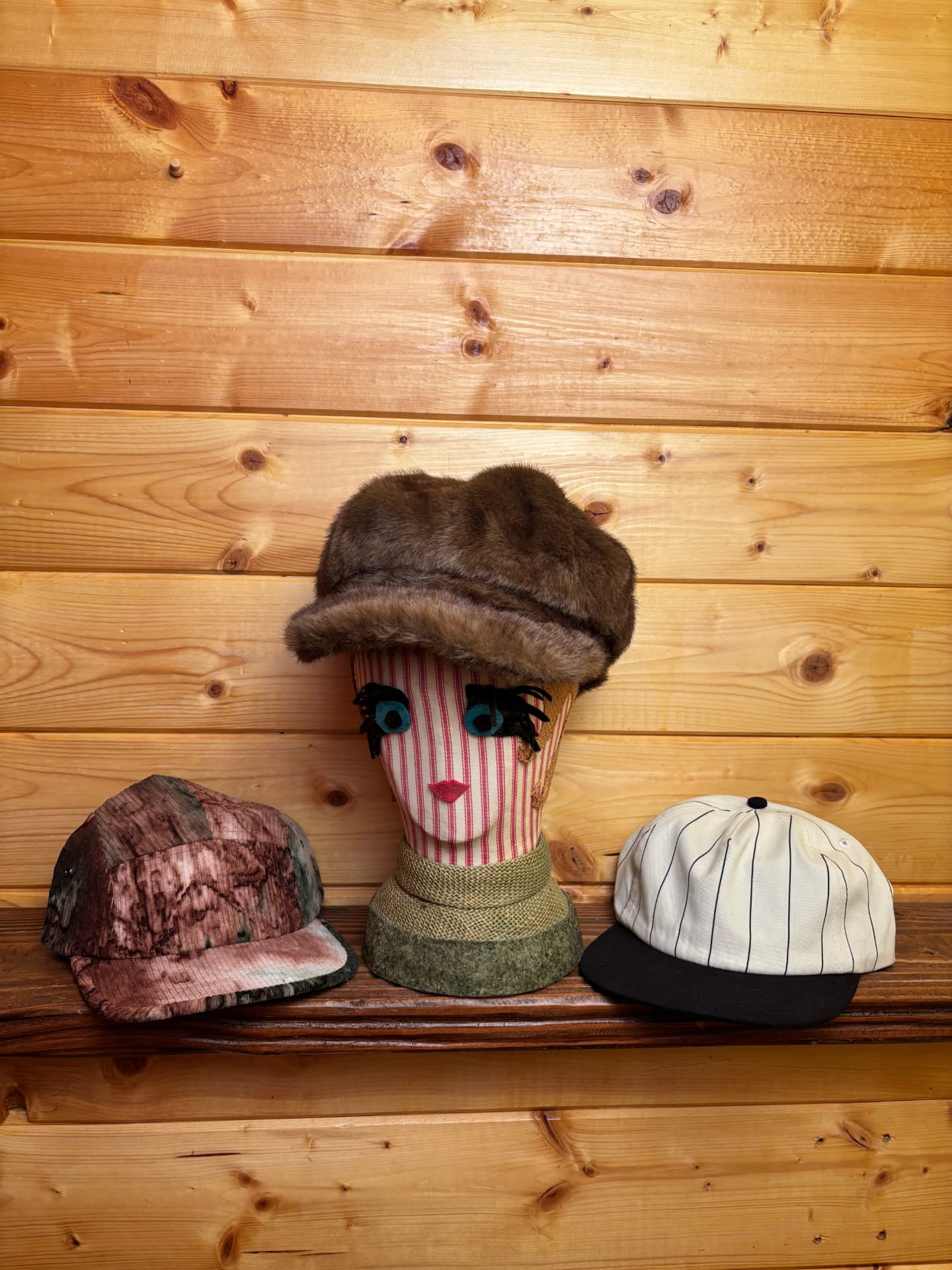 Three caps including a faux fur newsboy hat on a shelf