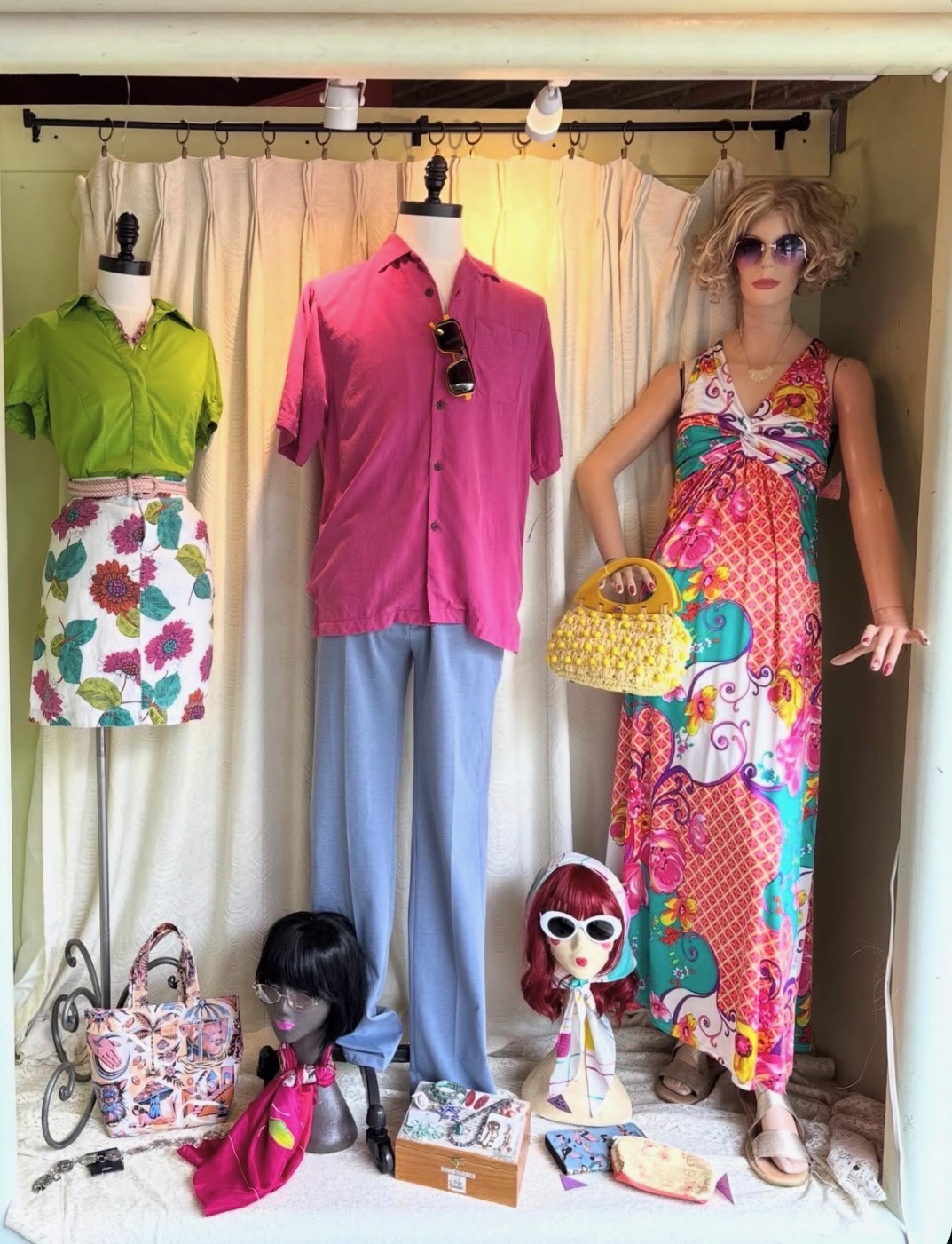 Vintage outfit display with floral maxi dress, pink shirt, and accessories